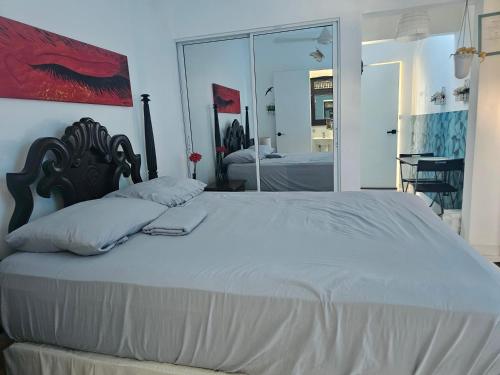 a bedroom with a large white bed and a mirror at AZUL PUERTO Del MALECON in San Felipe de Puerto Plata