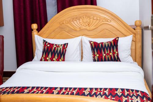 a bed with a wooden headboard and two pillows at Serenus Lounge in Senge