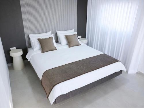 ein Schlafzimmer mit einem großen Bett mit weißen Laken und Kissen in der Unterkunft וילה Mandala אירוח&אירועים in Sājūr