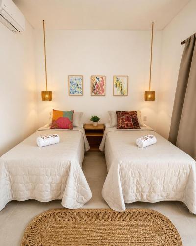 two beds with white sheets in a room at Villa Rita - Preá in Prea