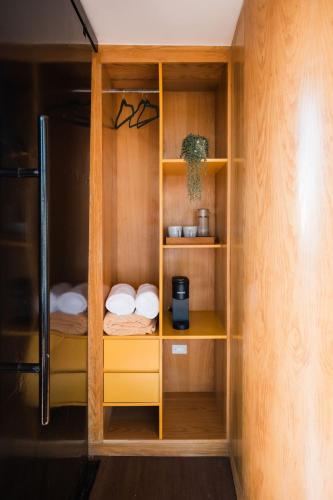 a closet with wooden shelves and a refrigerator at Primario Hotel Boutique in Ensenada