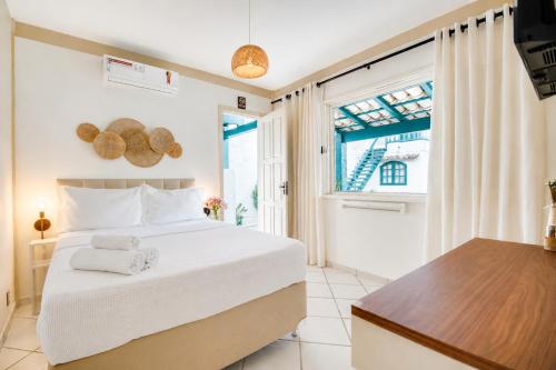 a bedroom with a large white bed and a window at Elsi Pousada in Búzios