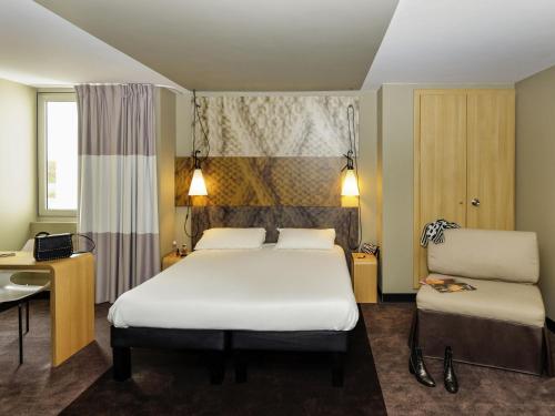 a hotel room with a bed and a desk at ibis Longwy Mexy in Mexy