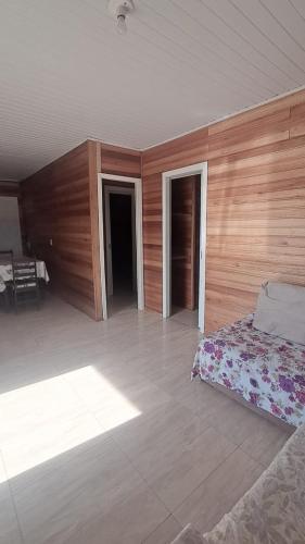 a bedroom with a bed and a wooden wall at Otima casa com 2 quartos em Tramandai in Tramandaí