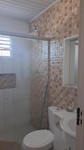 a bathroom with a toilet and a shower and a sink at Otima casa com 2 quartos em Tramandai in Tramandaí