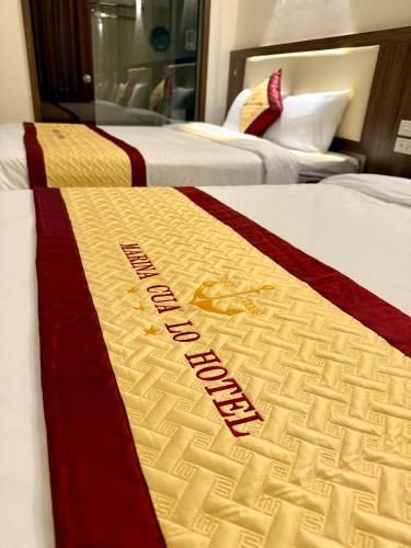 two beds in a hotel room with a hotel sign on them at Marina Cua Lo Hotel in Cửa Lô