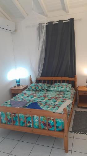 a bedroom with a wooden bed with a curtain at Bungalow vue sur mer in Sainte-Anne