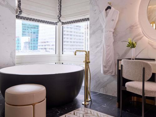 a bathroom with a black tub and a window at Sofitel New York in New York