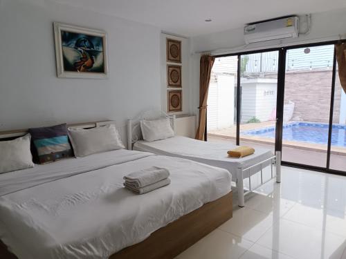 two beds in a bedroom with a view of a pool at jomtien 5BR villa in Pattaya South