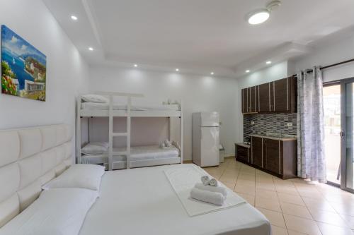 a white bedroom with a bed and a refrigerator at Poseidon Family Hotel Ksamil in Ksamil