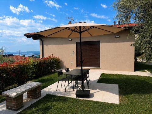 a table and chairs under an umbrella in a yard at La Casetta in Toscolano Maderno