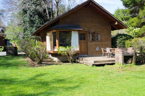 a small wooden cabin with a table in the yard at Cabañas Playa Linda in Pucón