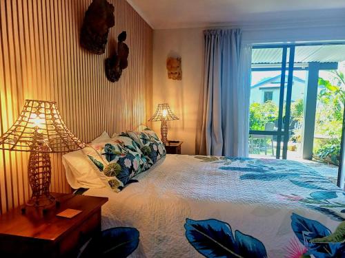 a bedroom with a bed with a lamp and a window at Driftwood Sands Studio in Tairua