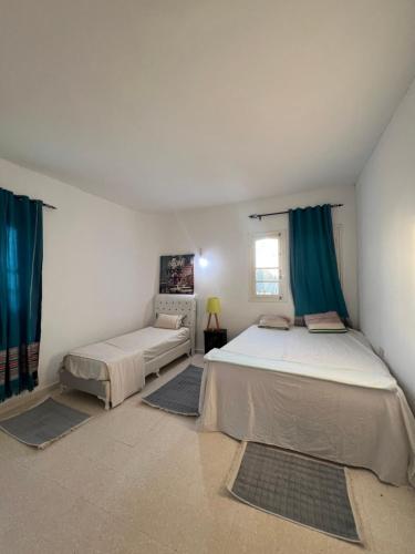 a bedroom with two beds and blue curtains at Villa sedghiani in El Guecheïne
