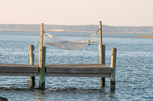 a hammock on a dock in a body of water at Sunny Shack in Black Point Landing
