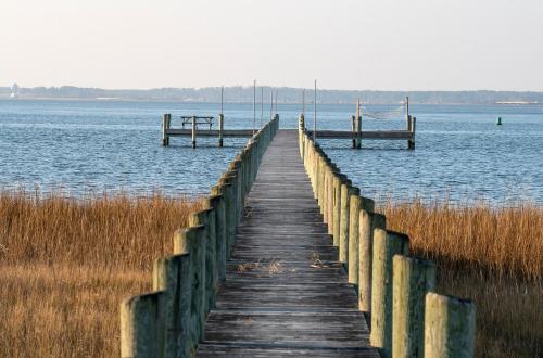 a wooden dock in the water with two benches at Sunny Shack in Black Point Landing