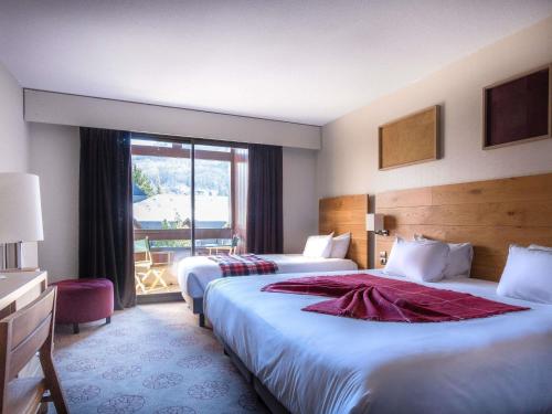a hotel room with two beds and a window at Mercure Saint-Lary in Saint-Lary-Soulan