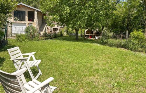 two white chairs sitting in the grass in a yard at Lovely Home In Podhum With House A Panoramic View in Podhum