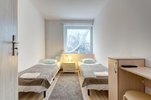 グダニスクにあるApartament Gdańsk Sun and Seaのベッド2台と窓が備わる小さな客室です。
