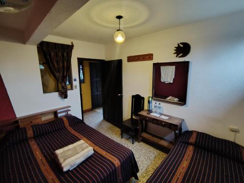 a bedroom with two beds and a desk and a mirror at Hotel Sueño Real in Panajachel