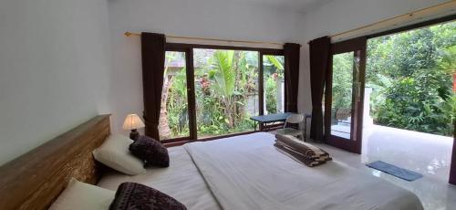 a bedroom with a large bed and large windows at Praba House in Ubud