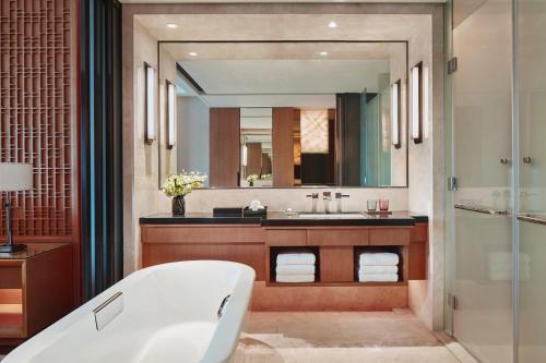 a bathroom with a tub and a large mirror at Zhuhai Marriott Hotel in Zhuhai