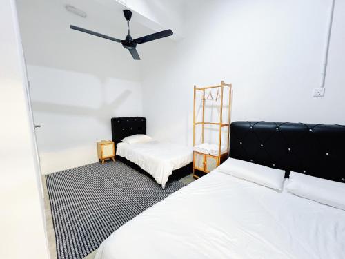 a bedroom with two beds and a chair and a fan at My Room Sri Aman in Kampong Lamanak