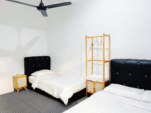a room with two beds and a black chair at My Room Sri Aman in Kampong Lamanak