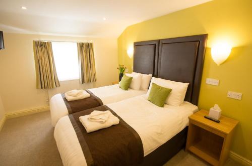 a hotel room with two beds with towels on them at Wakefield Limes Lodge in Wakefield