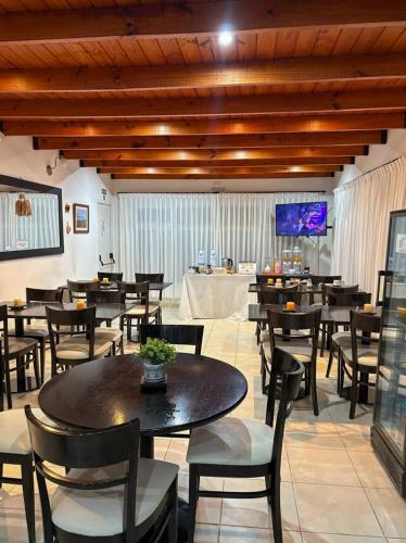 a dining room with tables and chairs and a television at Hosteria Posada Drake in Puerto San Julián