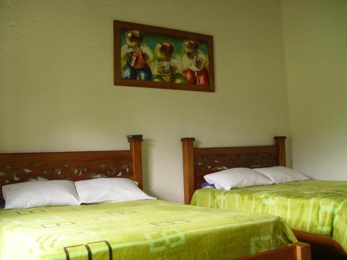 a room with two beds and a painting on the wall at Casa Hotel Portón Campestre in Jardin