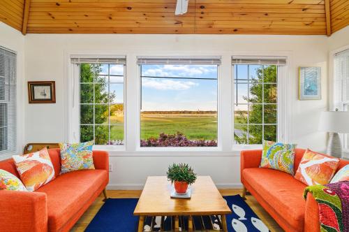 a living room with two orange couches and a table at To the Lighthouse in Birch Town