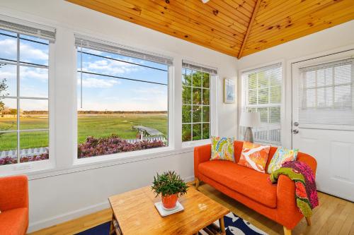 a living room with a orange couch and windows at To the Lighthouse in Birch Town