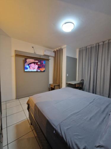 a bedroom with a bed and a flat screen tv at Condomínio Inn Studio in Foz do Iguaçu