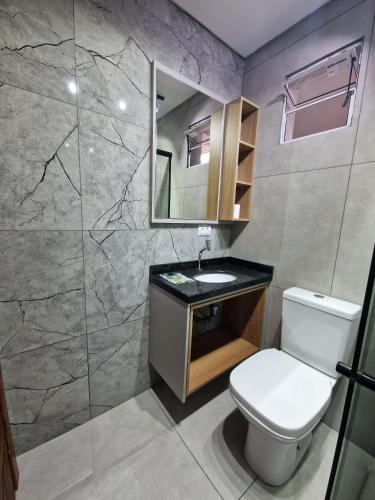 a bathroom with a toilet and a sink and a mirror at Condomínio Inn Studio in Foz do Iguaçu