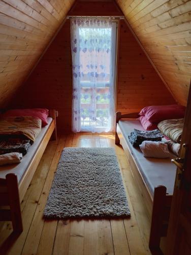 a attic room with two beds and a window at Domek Olchowiec 2 Nad Soliną in Olchowiec