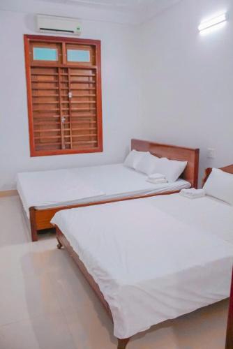 two beds in a room with a window at Tám bảy in Cửa Lô
