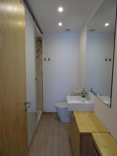 a bathroom with a sink and a toilet and a mirror at Casa do Bairro in Sesimbra