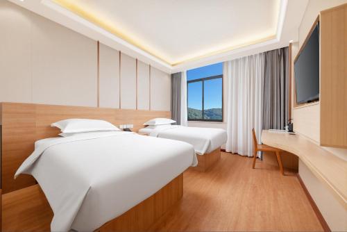 a hotel room with two beds and a television at Tangshan Yipin Hot Spring Hotel in Nanjing