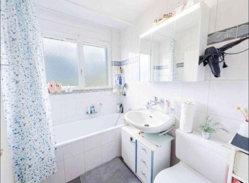 a white bathroom with a sink and a tub and a toilet at Einfamilienhaus in Amriswil in Amriswil