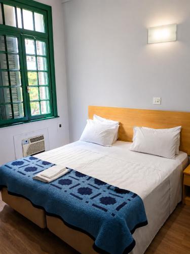 a bedroom with a large bed with a blue blanket on it at Hotel Internacional São Paulo in São Paulo
