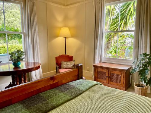 a bedroom with a bed and a table and two windows at Wisteria Villa in Russell