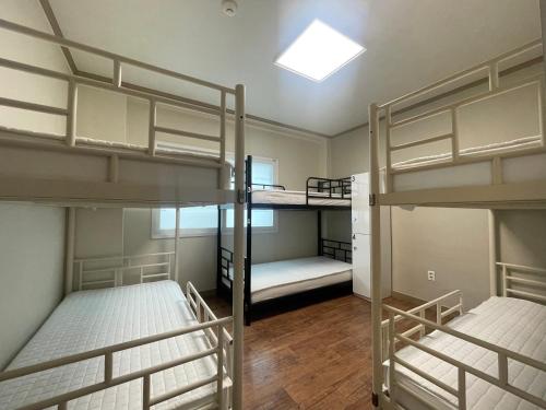 a room with three bunk beds and a skylight at Baramgot Guesthouse in Gyeongju