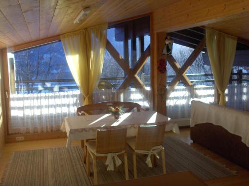 ein Esszimmer mit einem Tisch, Stühlen und Fenstern in der Unterkunft Ferienwohnung Barbara Mair in Dölsach
