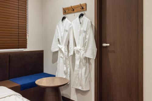 three white robes hanging on a rack in a room at Onjae Stay Seongsu in Seoul