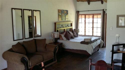 GrootvleiにあるWarembo Lodgeのベッドルーム1室(ベッド1台、ソファ、椅子付)