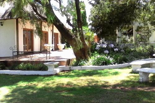 a garden with benches and a tree and flowers at Warembo Lodge in Grootvlei