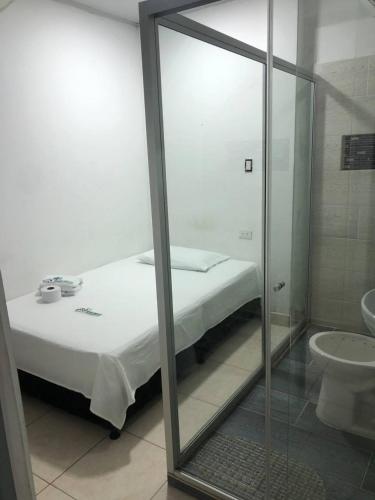 a room with a bed and a glass shower door at Casa Hotel Ortiz in Apartadó
