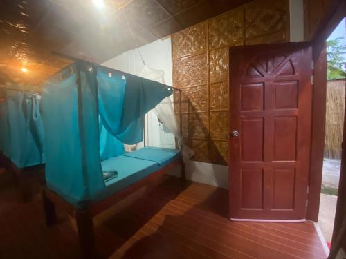 a room with a blue bed and a red door at Be My Guest Hostel in Panglao Island