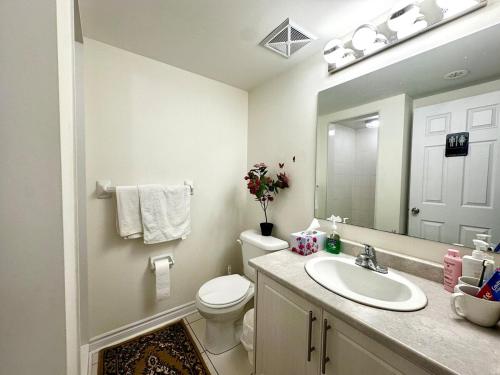 a bathroom with a sink and a toilet and a mirror at Comfortable 2BR Getaway with Extra Lounge Space in Toronto